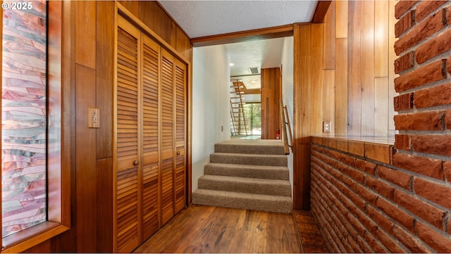 hallway featuring stairway, wood walls, wood finished floors, visible vents, and a textured ceiling