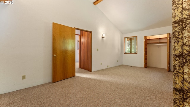 unfurnished bedroom featuring carpet flooring, high vaulted ceiling, and a closet