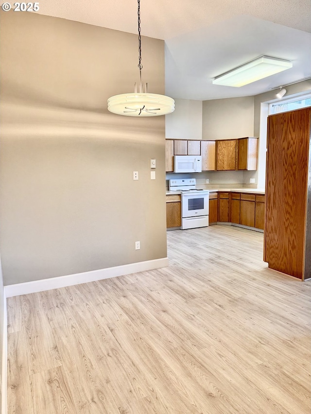 kitchen featuring white appliances, decorative light fixtures, and light wood-type flooring