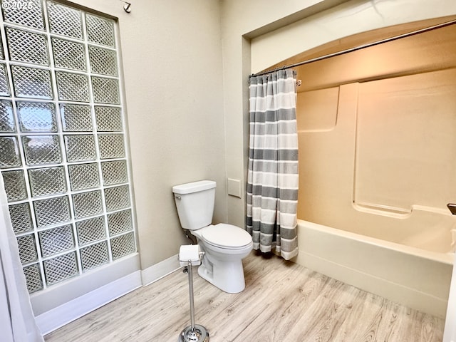 bathroom with hardwood / wood-style flooring, toilet, and shower / bath combo with shower curtain