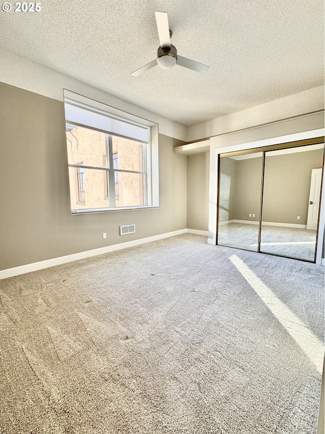 unfurnished bedroom featuring ceiling fan, carpet, a closet, and a textured ceiling