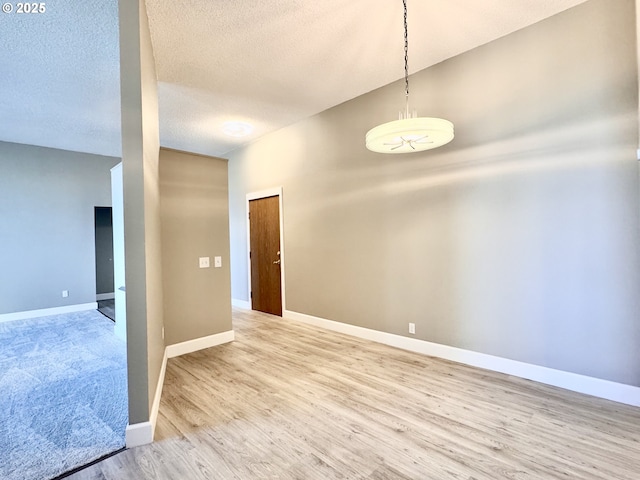 unfurnished room with a textured ceiling and light hardwood / wood-style floors