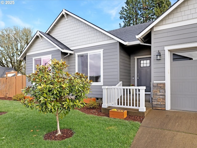 view of front facade with a garage, a shingled roof, fence, and a front lawn