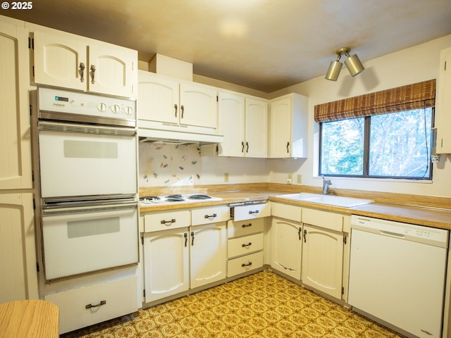 kitchen with sink, white appliances, and white cabinets