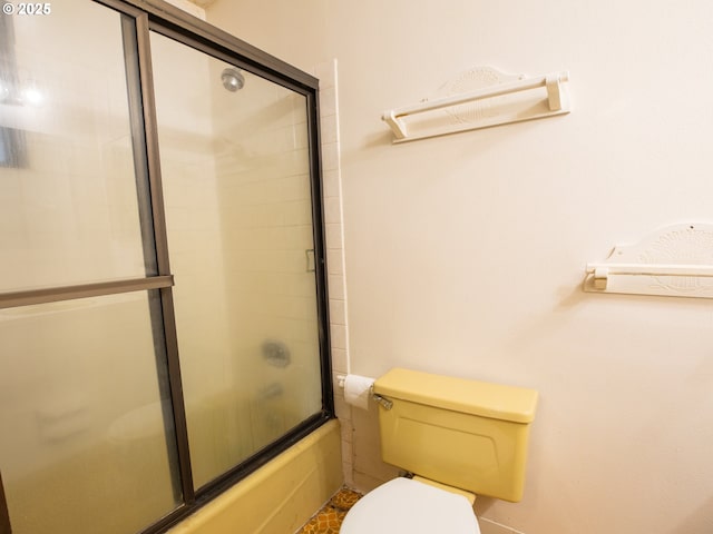 bathroom featuring combined bath / shower with glass door and toilet