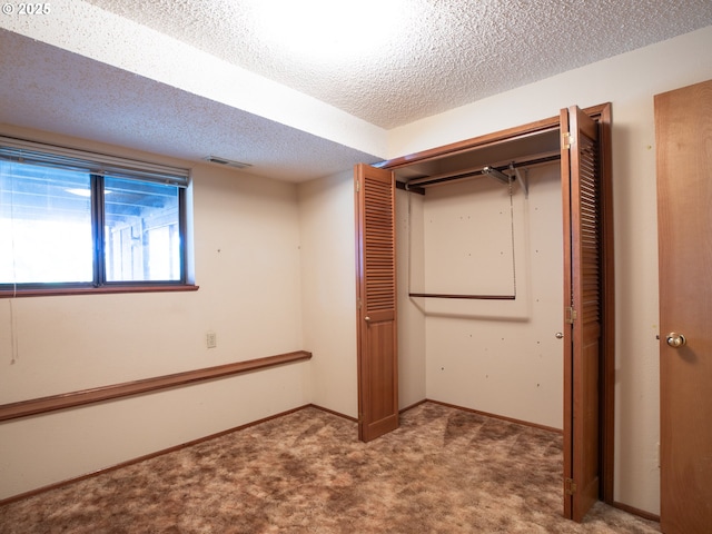 interior space featuring a closet, carpet floors, and a textured ceiling