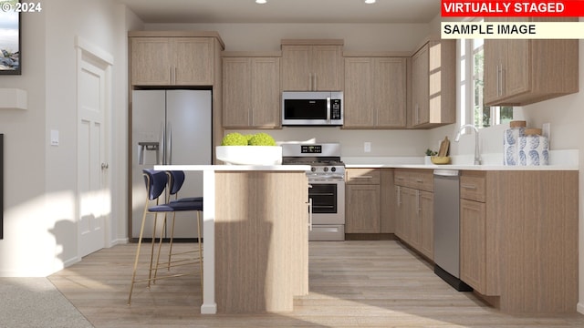kitchen with appliances with stainless steel finishes, a breakfast bar, light countertops, a center island, and recessed lighting