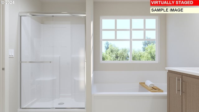 full bathroom featuring vanity, a bath, and a stall shower