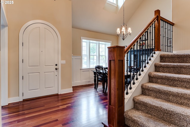 foyer with visible vents, high vaulted ceiling, dark wood-style floors, a notable chandelier, and stairs