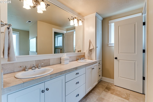 bathroom with visible vents, a sink, tile patterned flooring, and double vanity