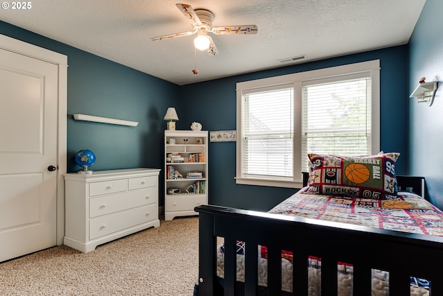 bedroom with visible vents, a ceiling fan, a textured ceiling, and light colored carpet