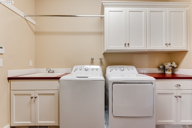 laundry area with a sink, independent washer and dryer, and cabinet space