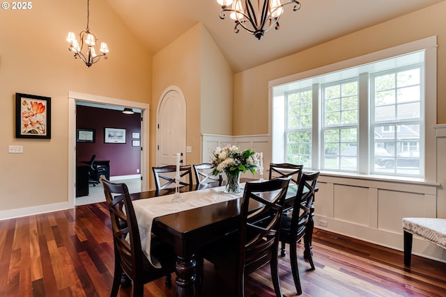 dining area featuring a notable chandelier, dark wood-type flooring, and a decorative wall