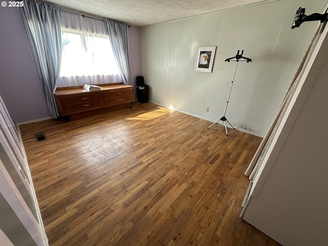 unfurnished bedroom with visible vents, a textured ceiling, and hardwood / wood-style flooring