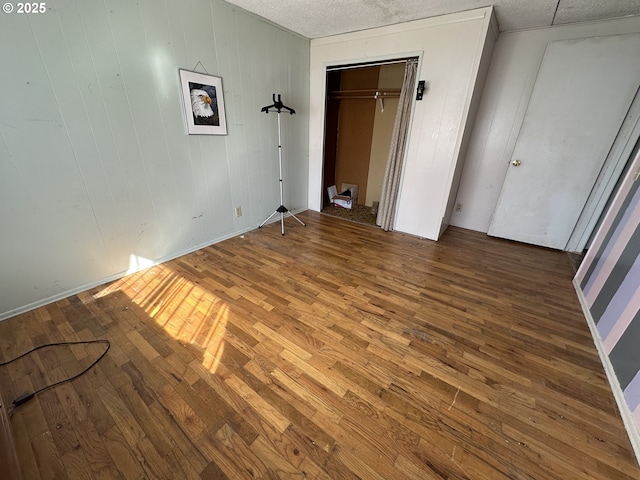 unfurnished bedroom with a closet, a textured ceiling, and wood finished floors