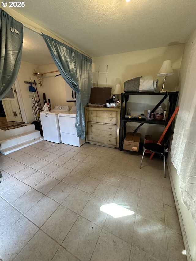 laundry area featuring light tile patterned floors, laundry area, washer and dryer, and a textured ceiling