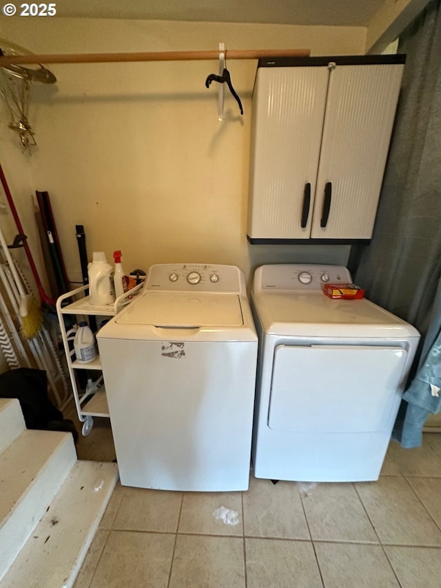 laundry room with washing machine and clothes dryer, light tile patterned floors, and cabinet space