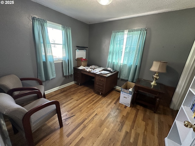 office with a textured ceiling, light wood-type flooring, and baseboards