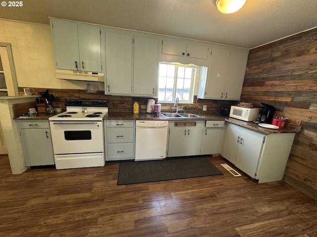 kitchen with a sink, white appliances, dark countertops, and under cabinet range hood