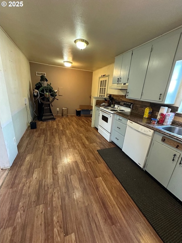 kitchen with visible vents, under cabinet range hood, dark countertops, dark wood finished floors, and white appliances