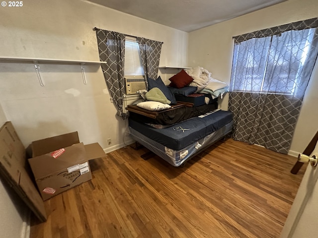 bedroom with baseboards, multiple windows, and wood finished floors