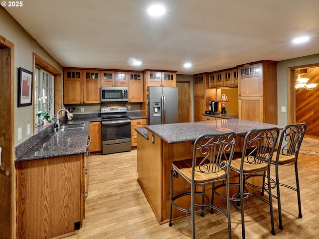 kitchen with kitchen peninsula, a breakfast bar area, appliances with stainless steel finishes, light wood-type flooring, and sink