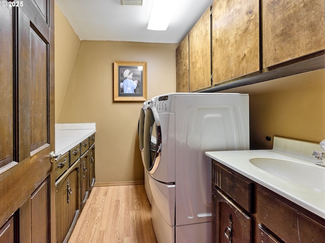 laundry room featuring cabinets, separate washer and dryer, sink, and light wood-type flooring