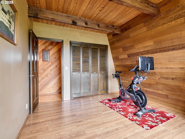 exercise room featuring light wood-type flooring, wood ceiling, and wooden walls