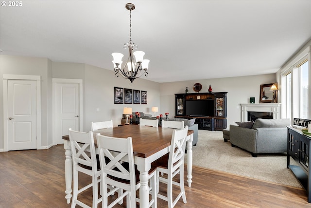 dining area with wood finished floors, a chandelier, and a fireplace