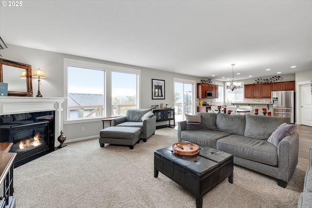 living room featuring a chandelier, recessed lighting, a fireplace with flush hearth, light colored carpet, and baseboards