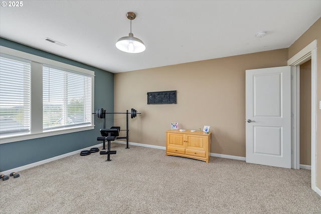 exercise room with light colored carpet and baseboards