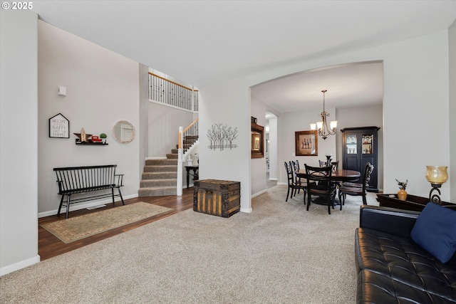 carpeted living room with arched walkways, baseboards, stairs, and an inviting chandelier