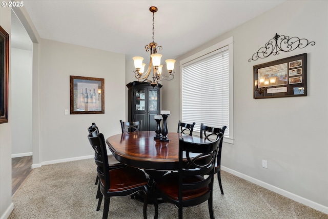 dining area with carpet flooring, an inviting chandelier, and baseboards