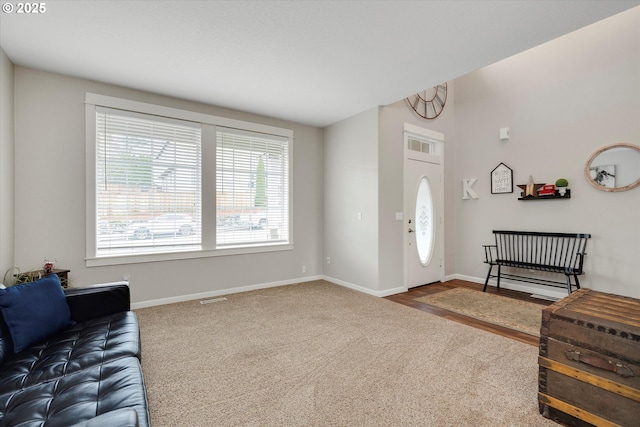 foyer entrance featuring visible vents, baseboards, and carpet flooring