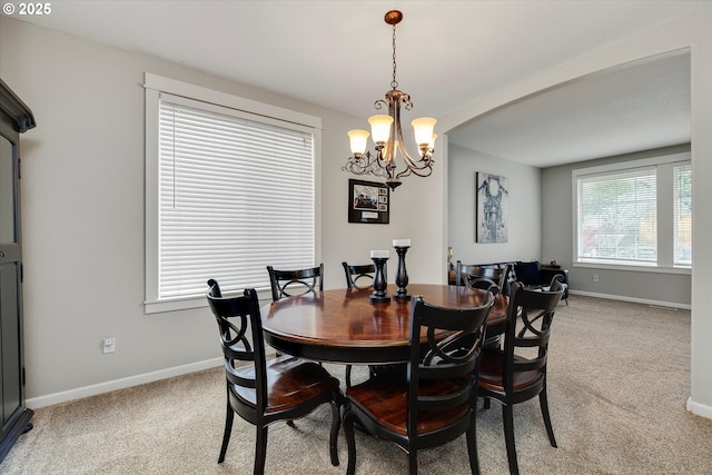 dining room with an inviting chandelier, baseboards, and light carpet