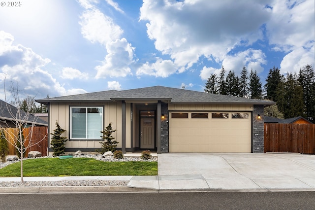 prairie-style home featuring fence, a front lawn, concrete driveway, a garage, and board and batten siding