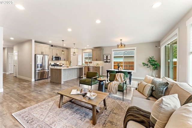 living area featuring recessed lighting, baseboards, and light wood-style floors