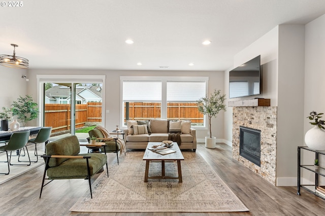 living area with recessed lighting, baseboards, wood finished floors, and a glass covered fireplace