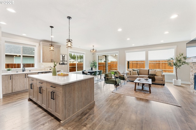 kitchen featuring a stone fireplace, a kitchen island, light countertops, and light wood-style floors