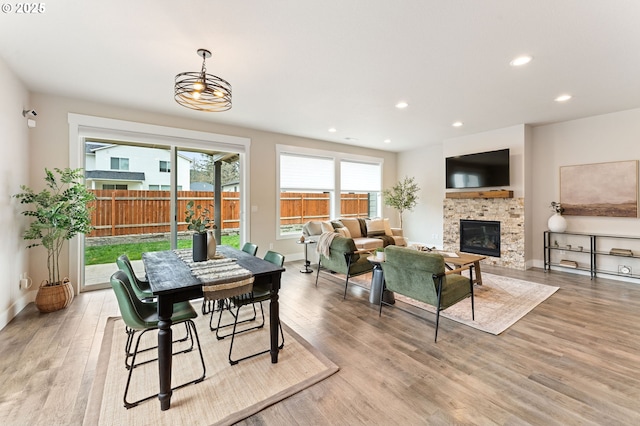 dining room with light wood finished floors, recessed lighting, a fireplace, and baseboards