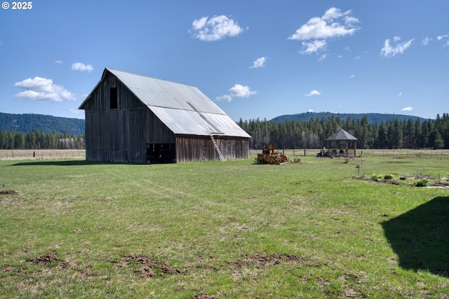 view of grassy yard featuring a view of rural / pastoral area, an outbuilding, a gazebo, and a mountain view