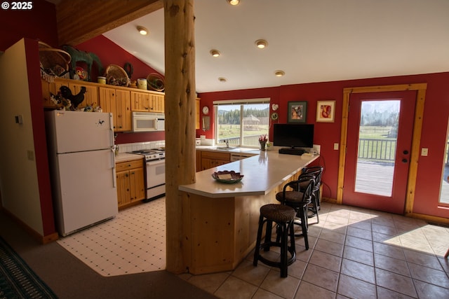 kitchen featuring white appliances, light countertops, a peninsula, vaulted ceiling, and a breakfast bar