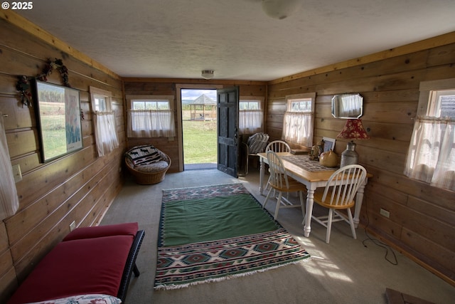 dining room with wooden walls, carpet floors, and a textured ceiling