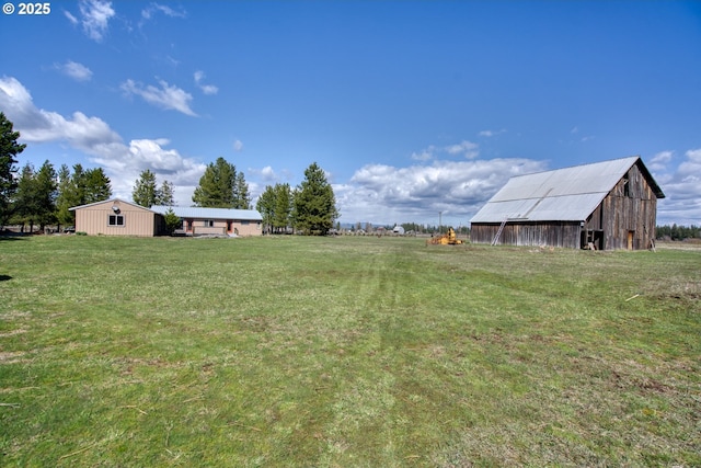 view of green lawn featuring an outdoor structure, a pole building, and a barn