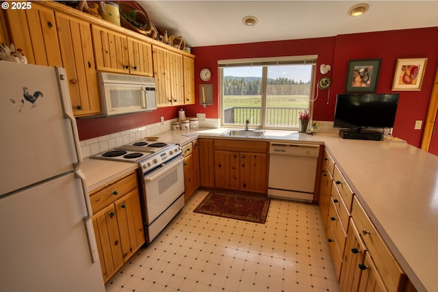 kitchen with white appliances, a sink, light countertops, light flooring, and a peninsula