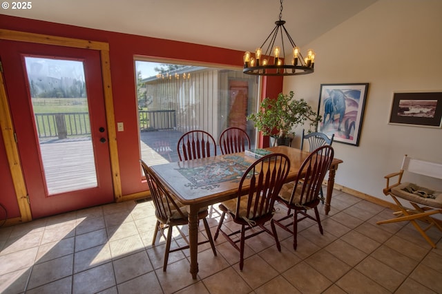 dining room with a chandelier, tile patterned flooring, lofted ceiling, and baseboards