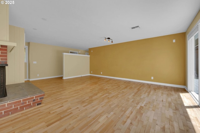 2720 Taylor St, Eugene, OR 97405 - unfurnished living room with light wood-type flooring, baseboards, a brick fireplace, and visible vents