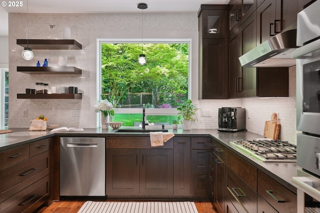kitchen featuring stainless steel appliances, a sink, dark countertops, and decorative backsplash