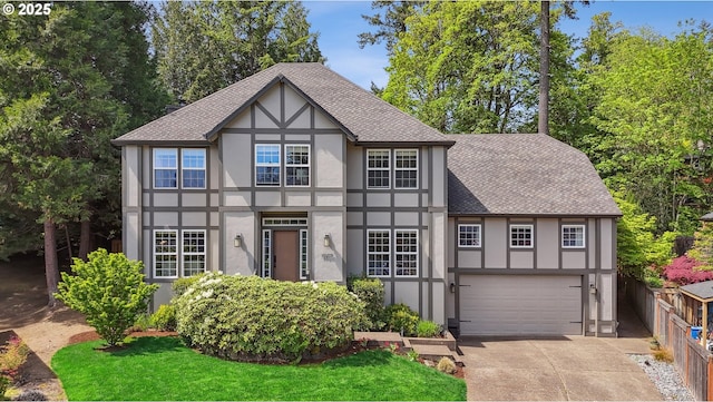 tudor house featuring stucco siding, roof with shingles, driveway, and an attached garage