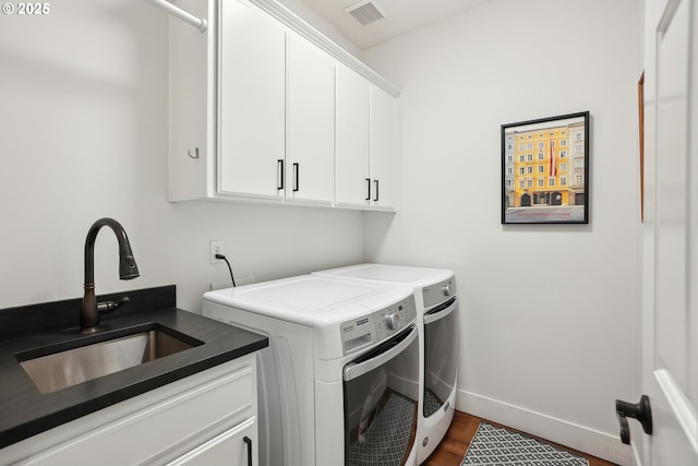laundry area with separate washer and dryer, cabinet space, wood finished floors, and baseboards